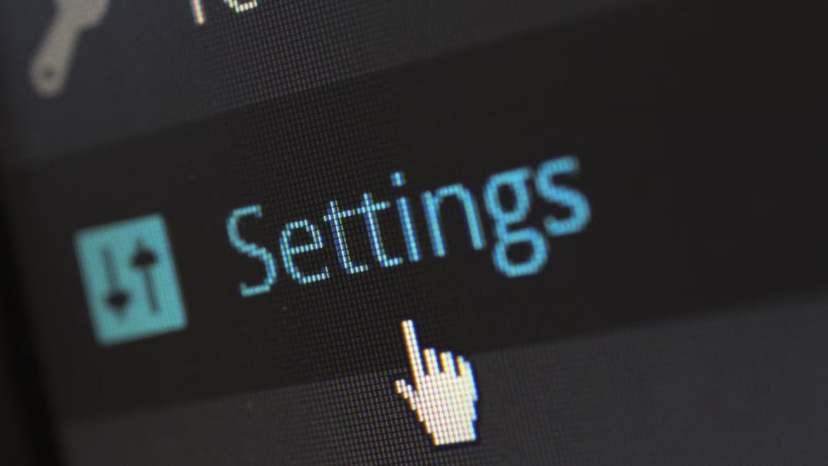 A close-up photo of a computer screen showing the settings button with a cursor hovering over it.